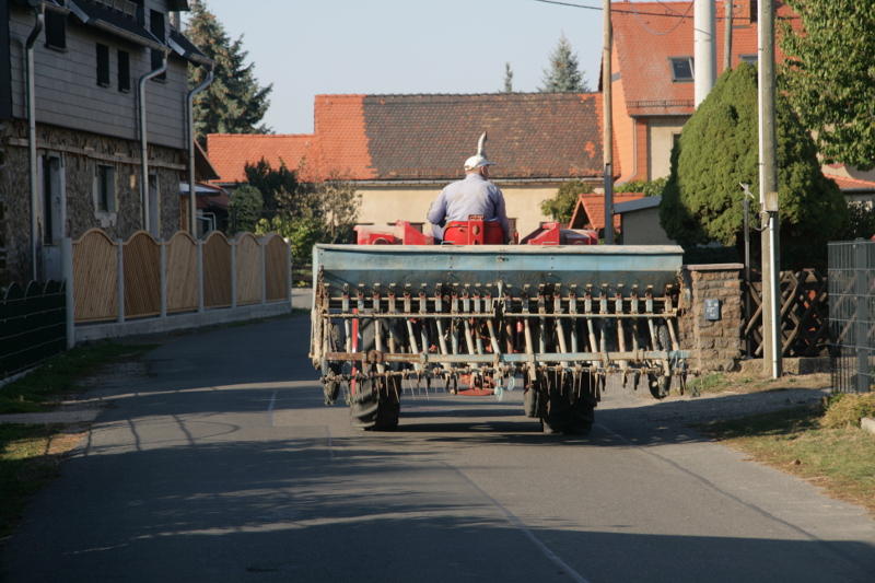 Traktor mit landwirtschaftlichem Gerät auf einer Dorfstraße